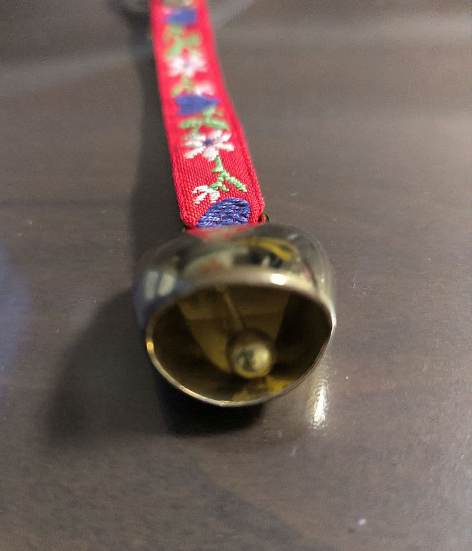Gold cowbell with red floral strap
